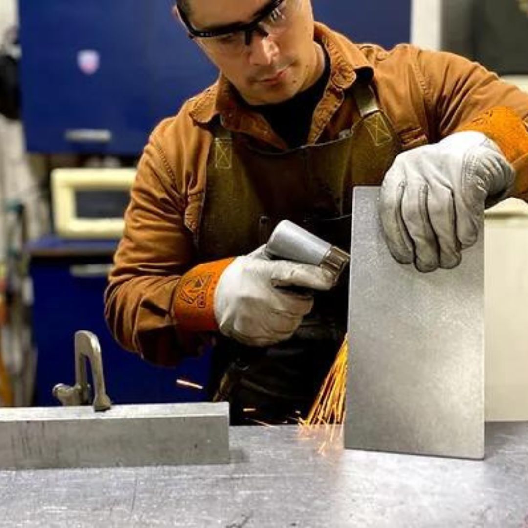 a worker welding the metal parts for the top of a Synergy Custom Fitness dumbbell rack.