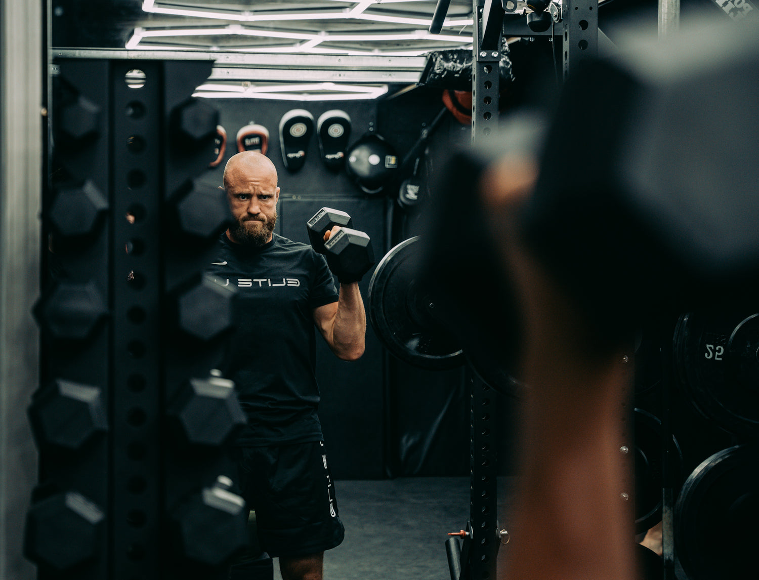 a man doing a workout with dumbbells next to a vertical dumbbell rack