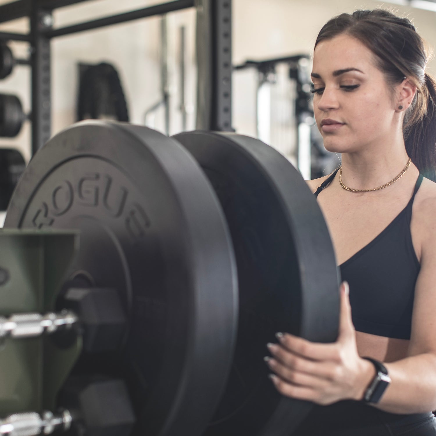 a woman pulling a weight plate off a storage rack