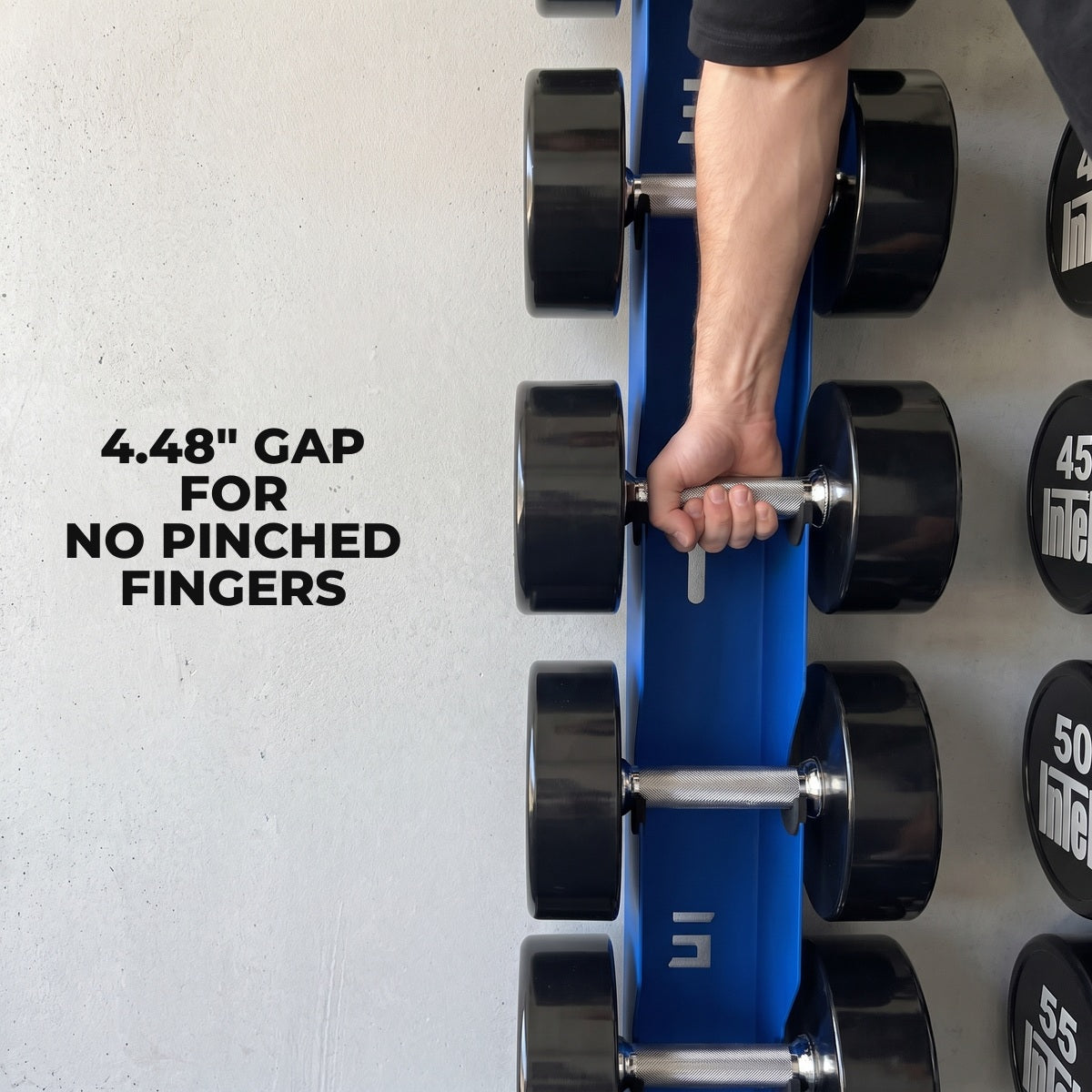 Hand reaching down to lift a dumbbell from the 4.48 inch gap of the Delta Elite wall mount