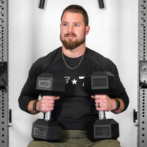 Seated lifter holding a pair of PRx straight handle hex dumbbells upright in front of the chest